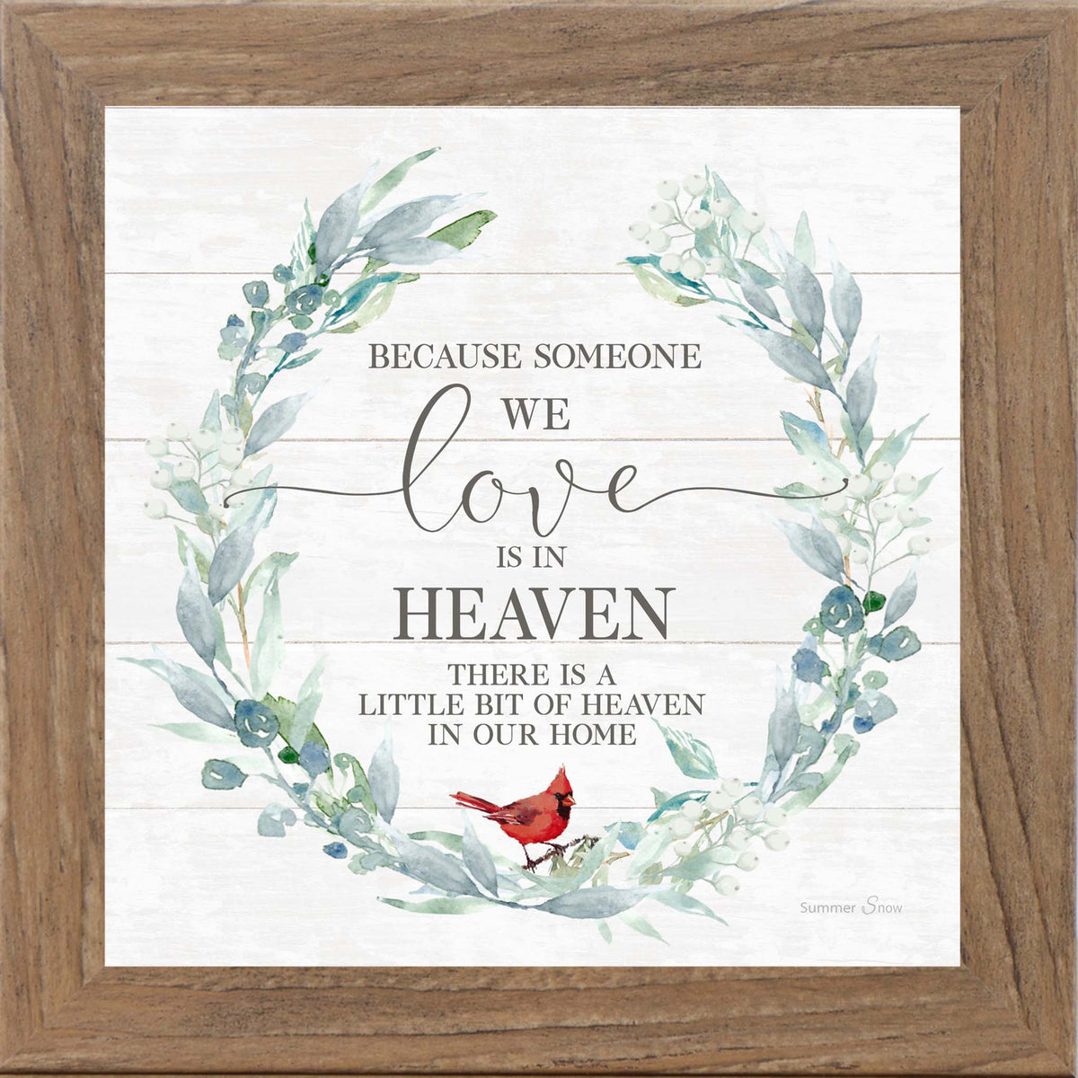 Square framed sympathy wall art featuring the phrase “Because someone we love is in heaven there is a little bit of heaven in our home” with a green floral wreath and red cardinal on slatted wood background