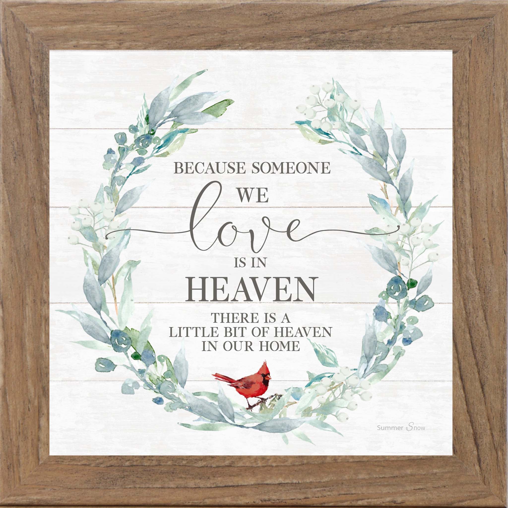 Square framed sympathy wall art featuring the phrase “Because someone we love is in heaven there is a little bit of heaven in our home” with a green floral wreath and red cardinal on slatted wood background