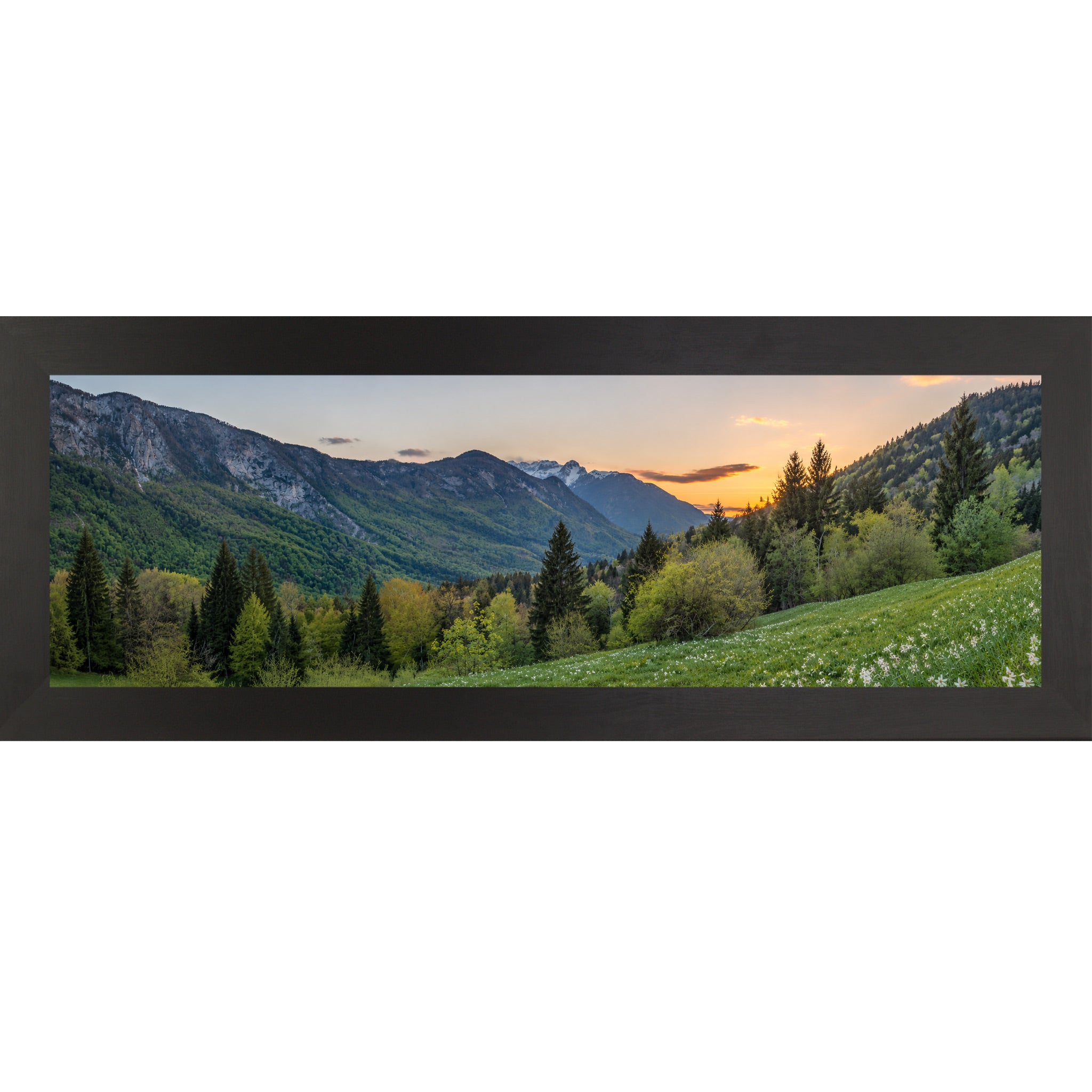 Black framed wide panoramic nature wall art featuring a mountain valley at sunset with snow-capped peaks evergreen forest and white wildflower meadow in the foreground