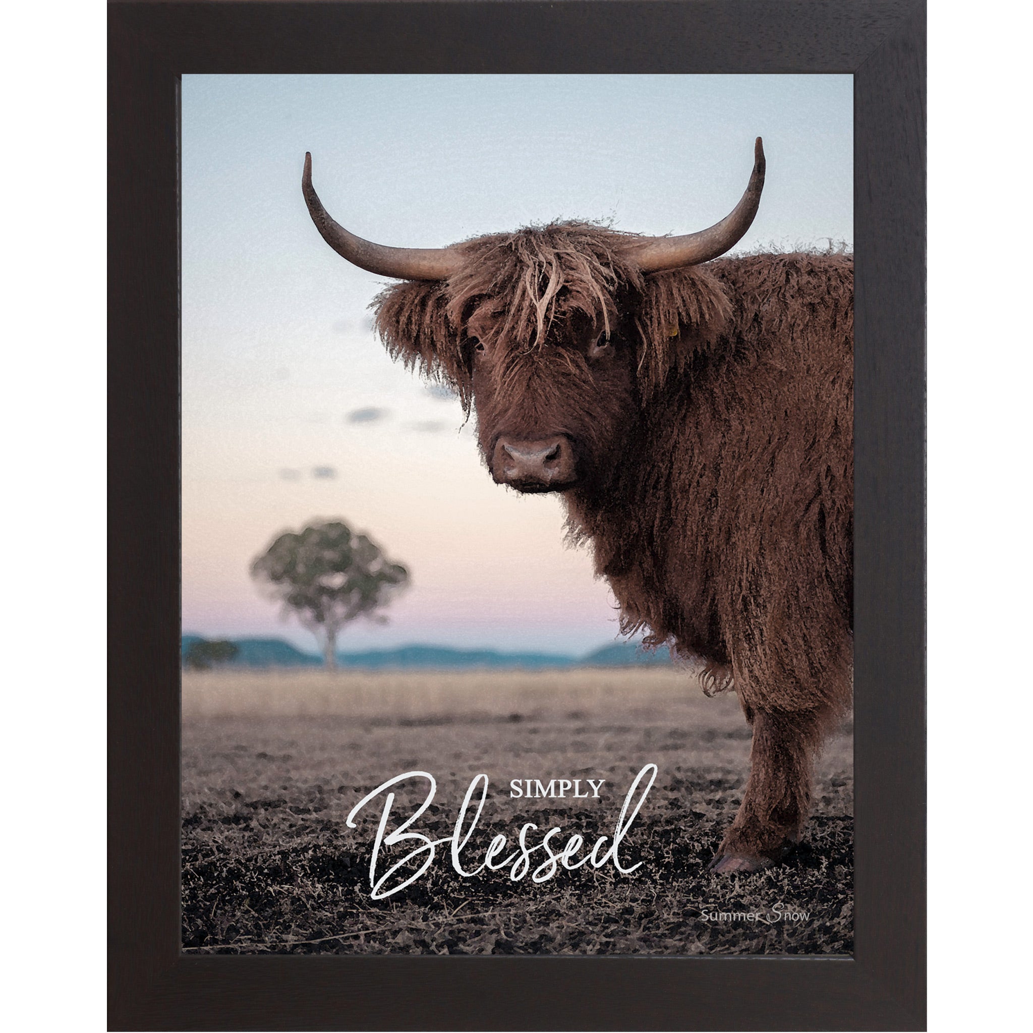 Black framed vertical farmhouse portrait wall art featuring a Highland cow with curved horns standing in a twilight field with a soft blush sky and lone tree with the words Simply Blessed