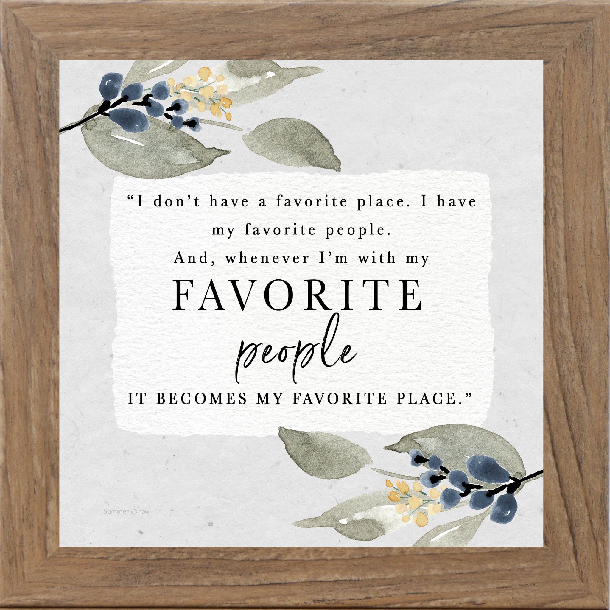Framed inspirational wall art with the quote “I don’t have a favorite place, I have my favorite people,” featuring soft green leaves with subtle blue and yellow blooms on a neutral background.