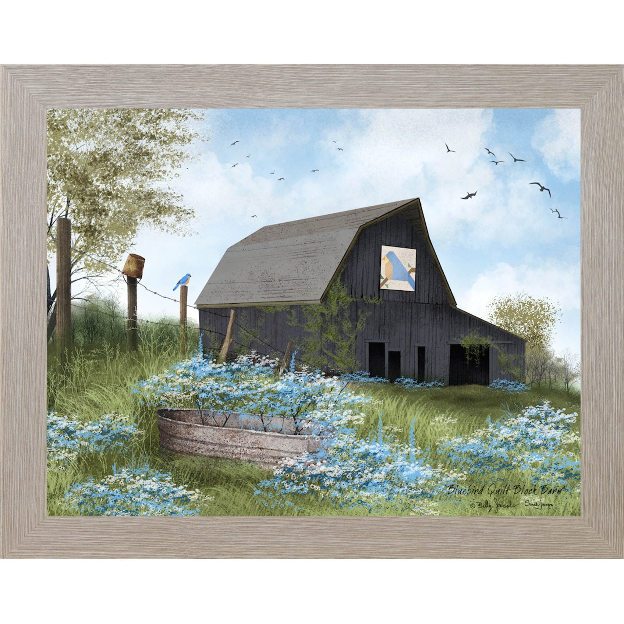 Monte Carlo framed Billy Jacobs Bluebird Quilt Block Barn wall art featuring a weathered gray gambrel barn with a bluebird quilt block on its face surrounded by blue and white wildflowers a metal stock tank a bluebird on a fence post and spring trees