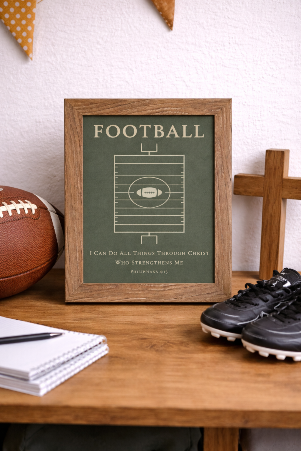 Room setting of a Christian football wall art featuring a minimalist football field design and Philippians 4:13 scripture on a green background. Framed in a farmtable colored frame.