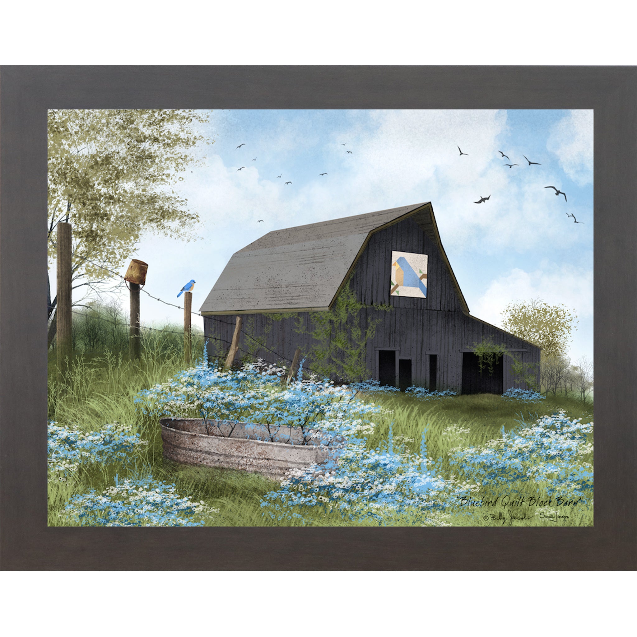 Slatewood framed Billy Jacobs Bluebird Quilt Block Barn wall art featuring a weathered gray gambrel barn with a bluebird quilt block on its face surrounded by blue and white wildflowers a metal stock tank a bluebird on a fence post and spring trees