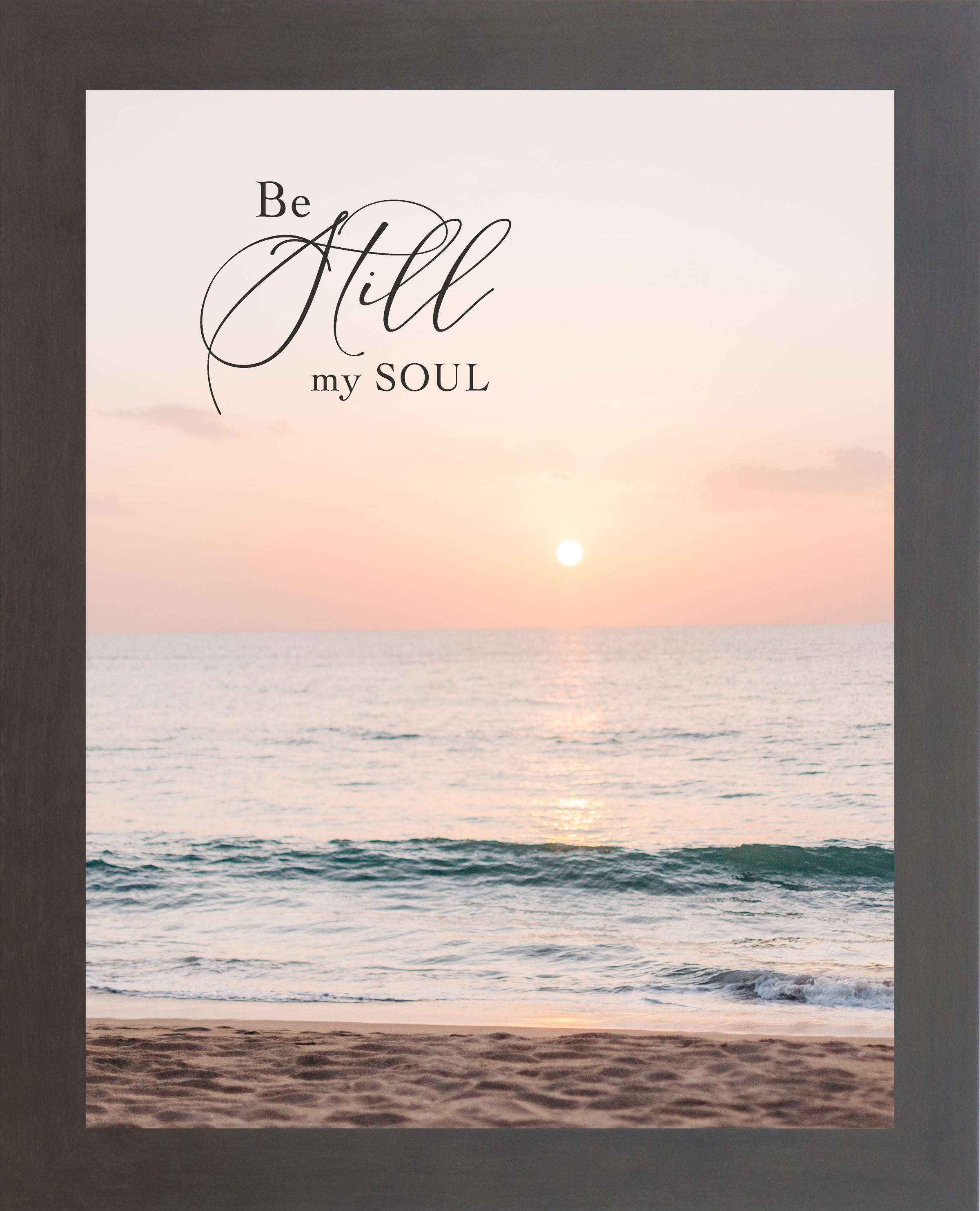 Slatewood framed portrait Christian wall art with the words Be Still My Soul in elegant script set against a soft peach and coral beach sunset with teal ocean waves and sandy shoreline
