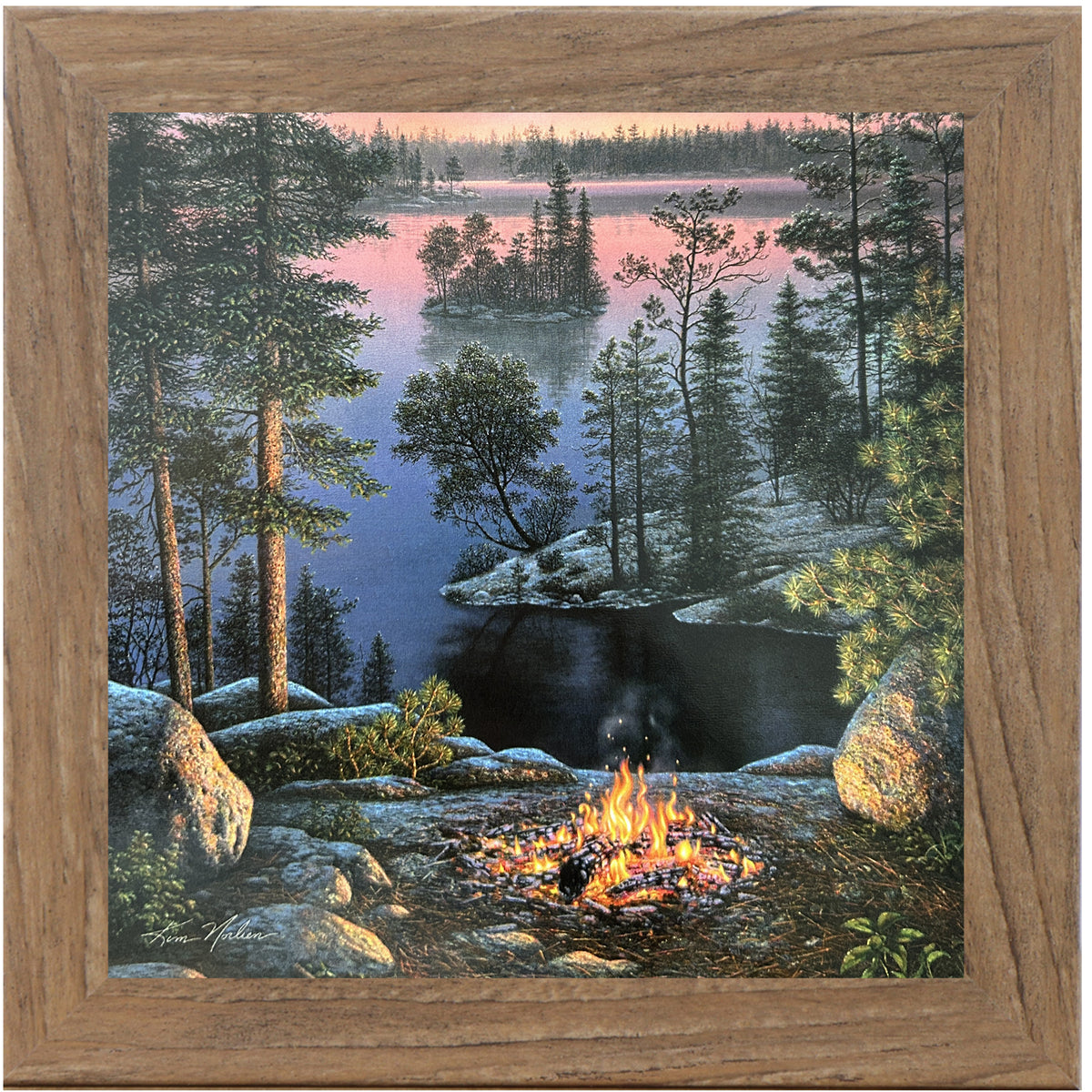 Framed 8x8 wall art showing a lakeside campfire at sunset with calm water, pine trees, and distant hills in soft golden tones. Art by Kim Norlien.